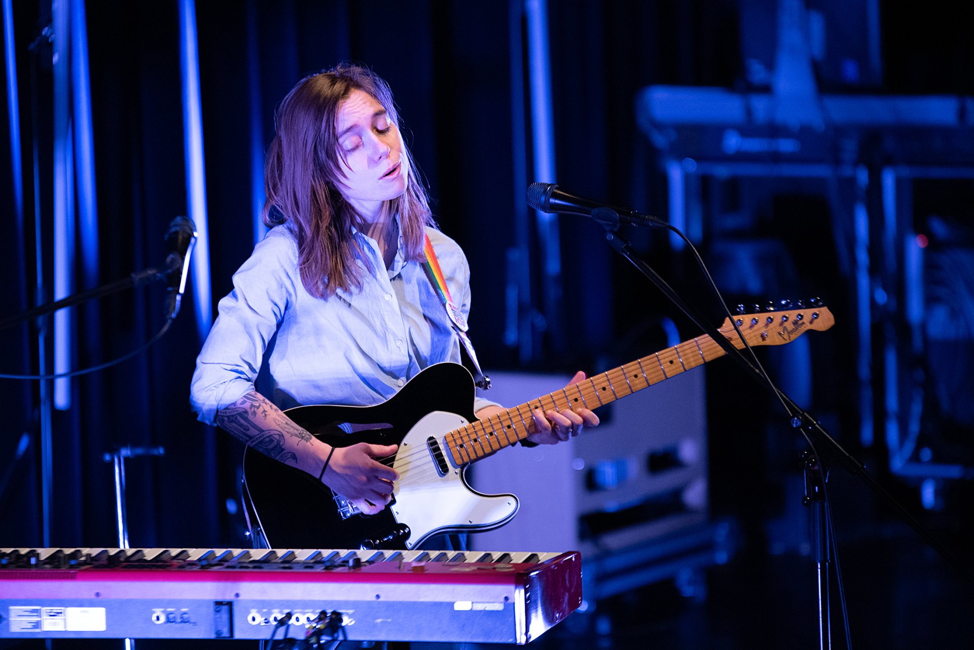 HD desktop wallpaper featuring an individual playing guitar on stage, with a serene expression, tagged as Julien Baker.