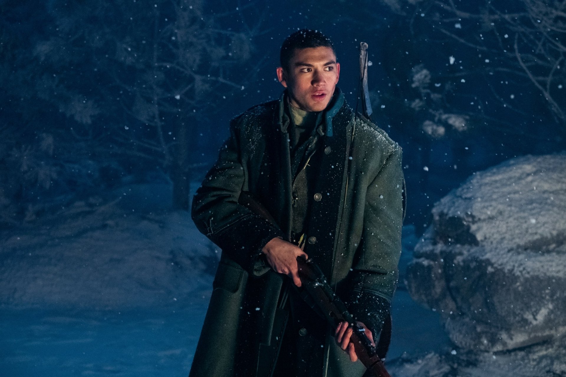 HD wallpaper of a character from Shadow and Bone in a wintery scene, dressed in a dark coat with a mysterious expression.