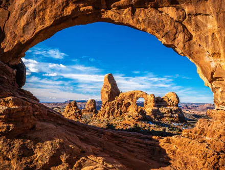 A stunning 4K Ultra HD wallpaper of Utah’s desert landscape showcasing natural rock arches under a bright blue sky in the USA.