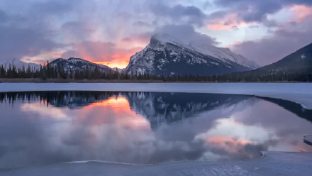 Winter dawn over a snow-capped mountain in Banff National Park, Canada, reflected in the calm lake waters, captured in stunning 4K Ultra HD.