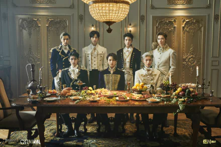 Seven young men in ornate military-style outfits pose around a lavish banquet table in an opulent room; music-themed 2K Quad HD PC desktop wallpaper.