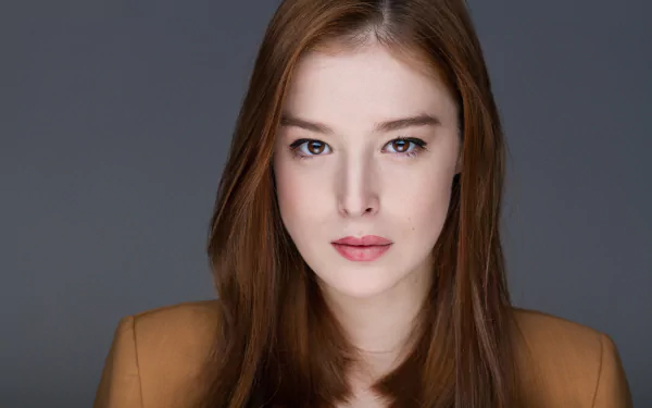 Close-up portrait of a redhead model with brown eyes, neutral expression, studio-lit against a gray backdrop — 5K Ultra HD desktop wallpaper.