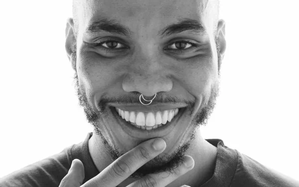 Black and white HD wallpaper of a smiling man with a nose ring, offering a bright and cheerful background.