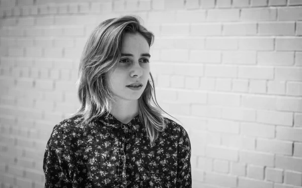 HD desktop wallpaper featuring a black and white photo of a person standing against a brick wall, evoking a contemplative mood.