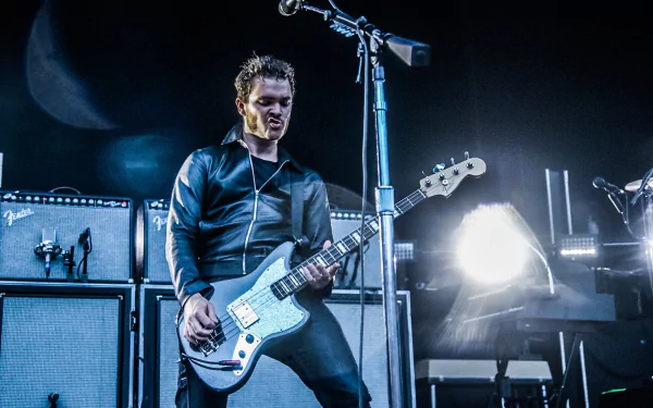 Rock musician performing live with electric guitar, bathed in stage lights, Royal Blood theme HD desktop wallpaper.