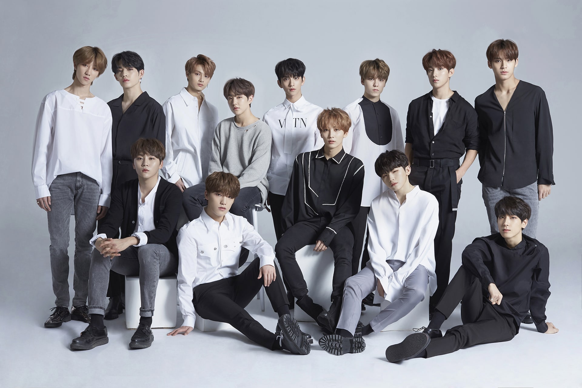 Group of thirteen individuals posing for a stylish HD desktop wallpaper, dressed in coordinated black and white outfits, suitable for fans with a tag of Seventeen.