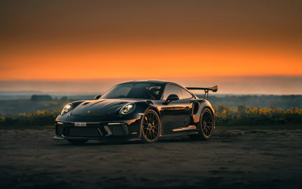 A black Porsche 911 GT3 sports car parked on a road at sunset, captured in stunning 4K Ultra HD quality.