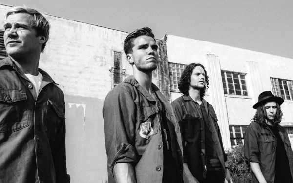 Black and white HD desktop wallpaper featuring the band KALEO, including a focused shot of a member, against an industrial building backdrop.