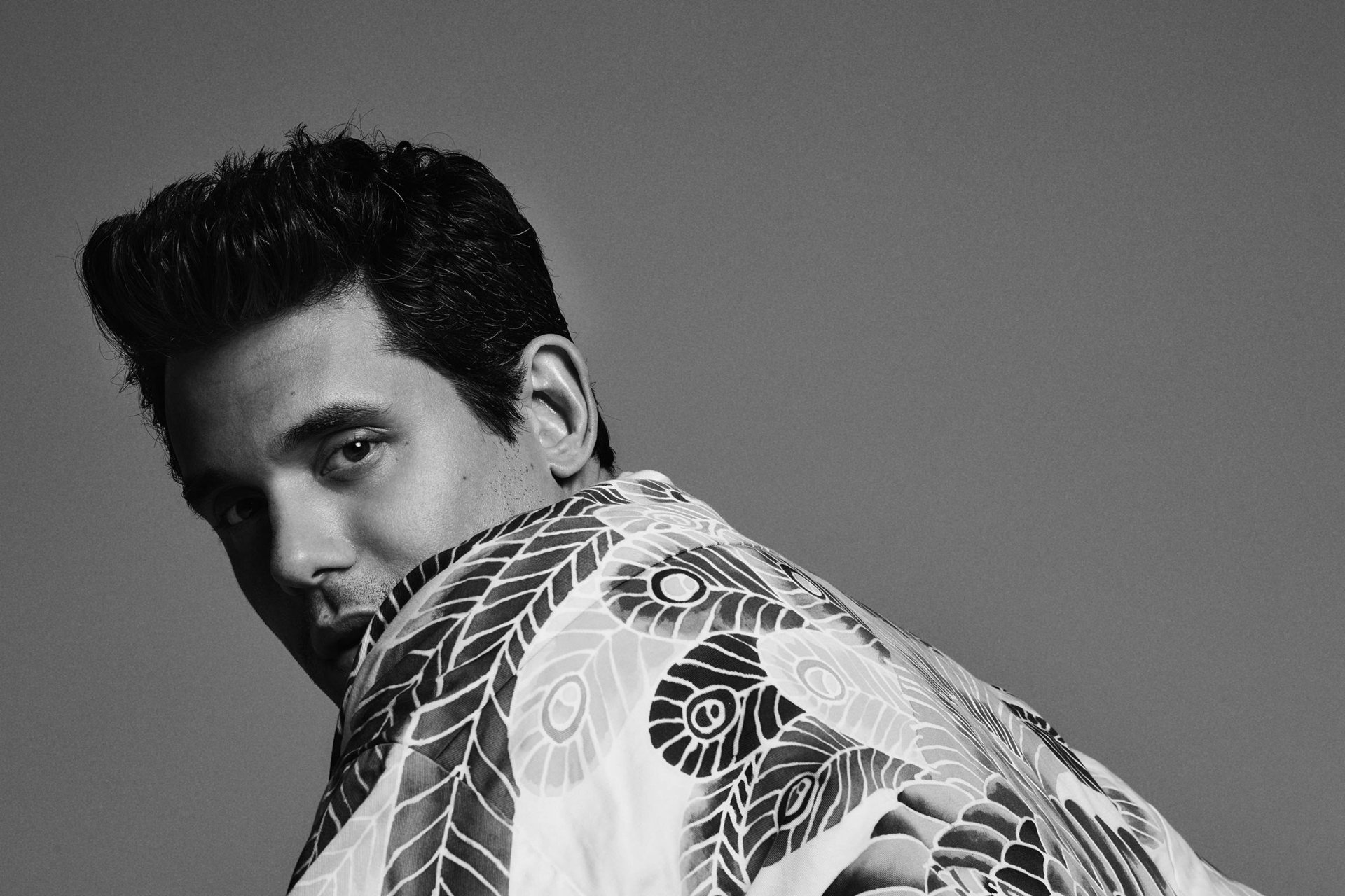 Black and white HD desktop wallpaper featuring a stylish man with a patterned jacket looking over his shoulder.