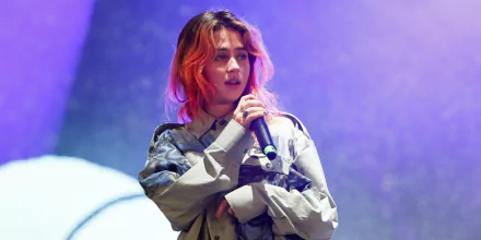 HD desktop wallpaper featuring a musician on stage with a microphone, bathed in purple stage lighting.