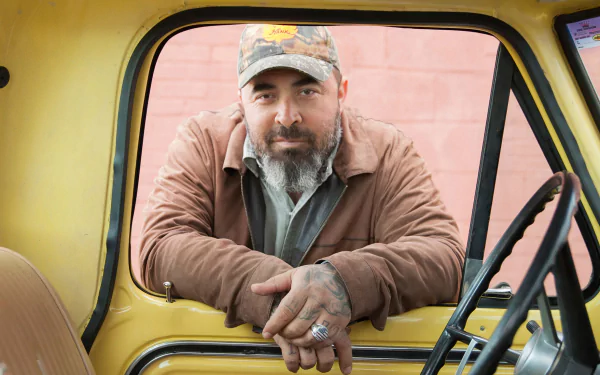 Man leaning on the window frame of a yellow vintage truck, HD desktop wallpaper and background.