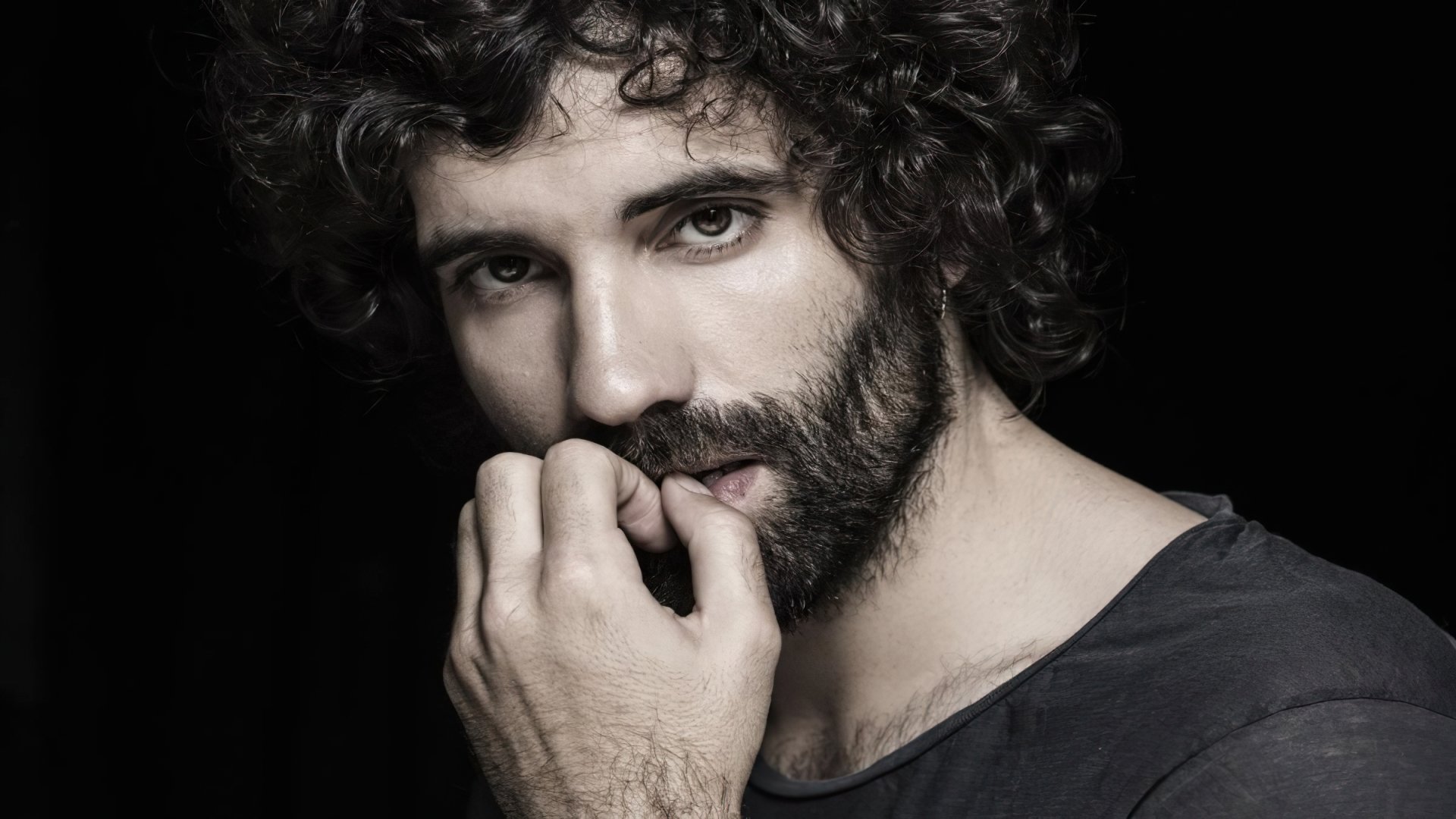 HD desktop wallpaper featuring celebrity Tamar Novas, showcasing his expressive gaze and curly hair against a dark background.