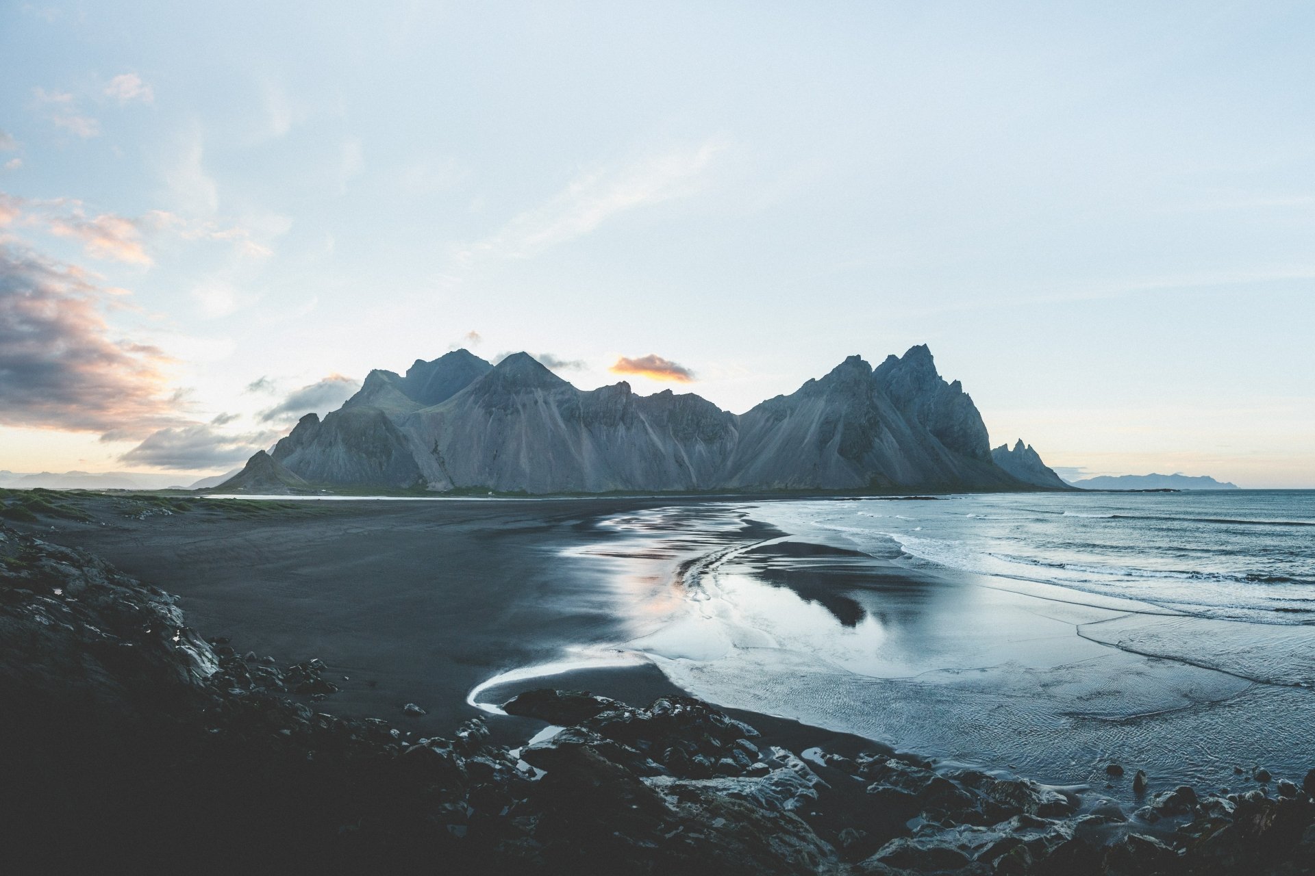 Vestrahorn Mountain rises sharply by a calm beach under a soft sky, captured in stunning detail for an 8K Ultra HD PC wallpaper showcasing nature's beauty.