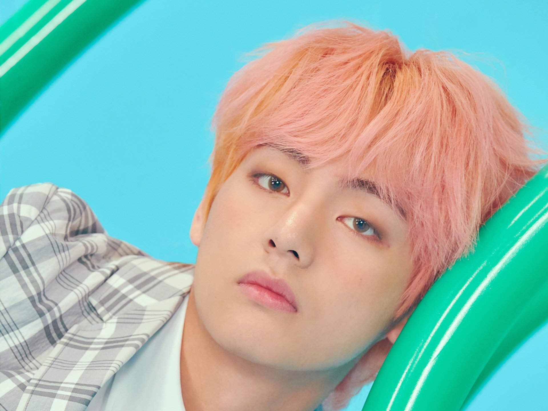 Close-up 4K Ultra HD wallpaper of V (Kim Taehyung), the K-pop singer from BTS, with pink hair and a soft expression set against a bright blue background.