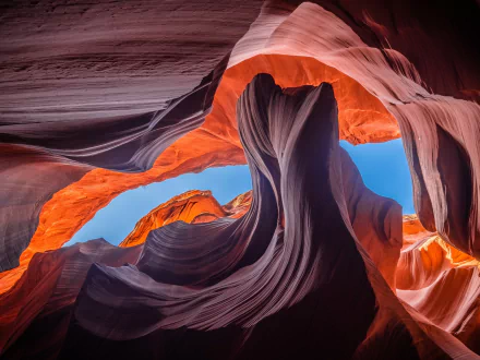 HD desktop wallpaper of Antelope Canyon captures stunning natural rock formations and a contrasting blue sky. This canyon image emphasizes the rich colors and textures of the landscape.