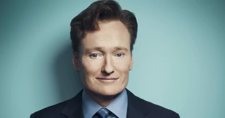 HD desktop wallpaper featuring a smiling man with red hair in a suit against a teal background.