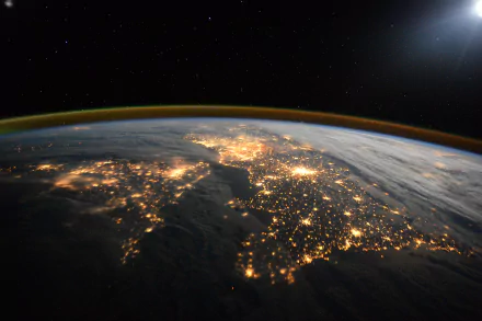 NASA's 4K Ultra HD view of Earth from space showcases illuminated city lights and the planet's atmosphere against the backdrop of the sun and stars.