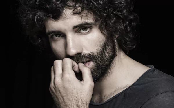 HD desktop wallpaper featuring celebrity Tamar Novas, showcasing his expressive gaze and curly hair against a dark background.