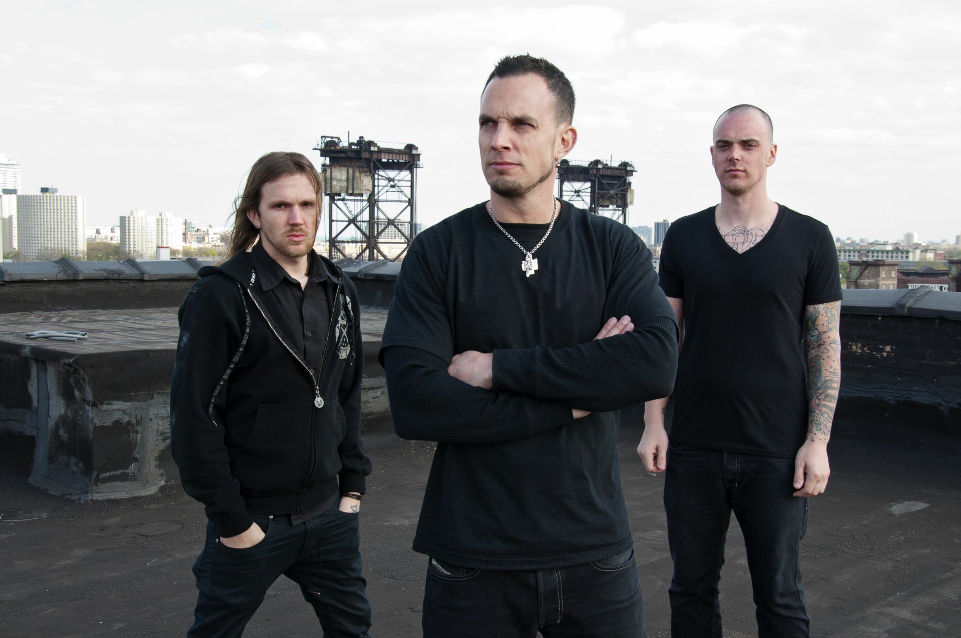 Three musicians pose confidently against an industrial backdrop, embodying the essence of Tremonti. This HD wallpaper captures their edgy style and musical energy.