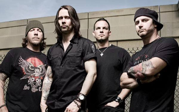 HD wallpaper featuring the band Tremonti, showcasing the four members posing confidently in a gritty outdoor setting with a chain-link fence in the background.