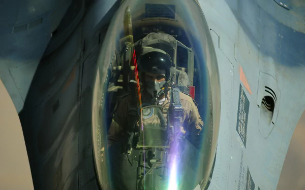 Close-up 4K Ultra HD image of a pilot in the cockpit of a General Dynamics F-16 Fighting Falcon military jet, showcasing intricate cockpit details and reflections.