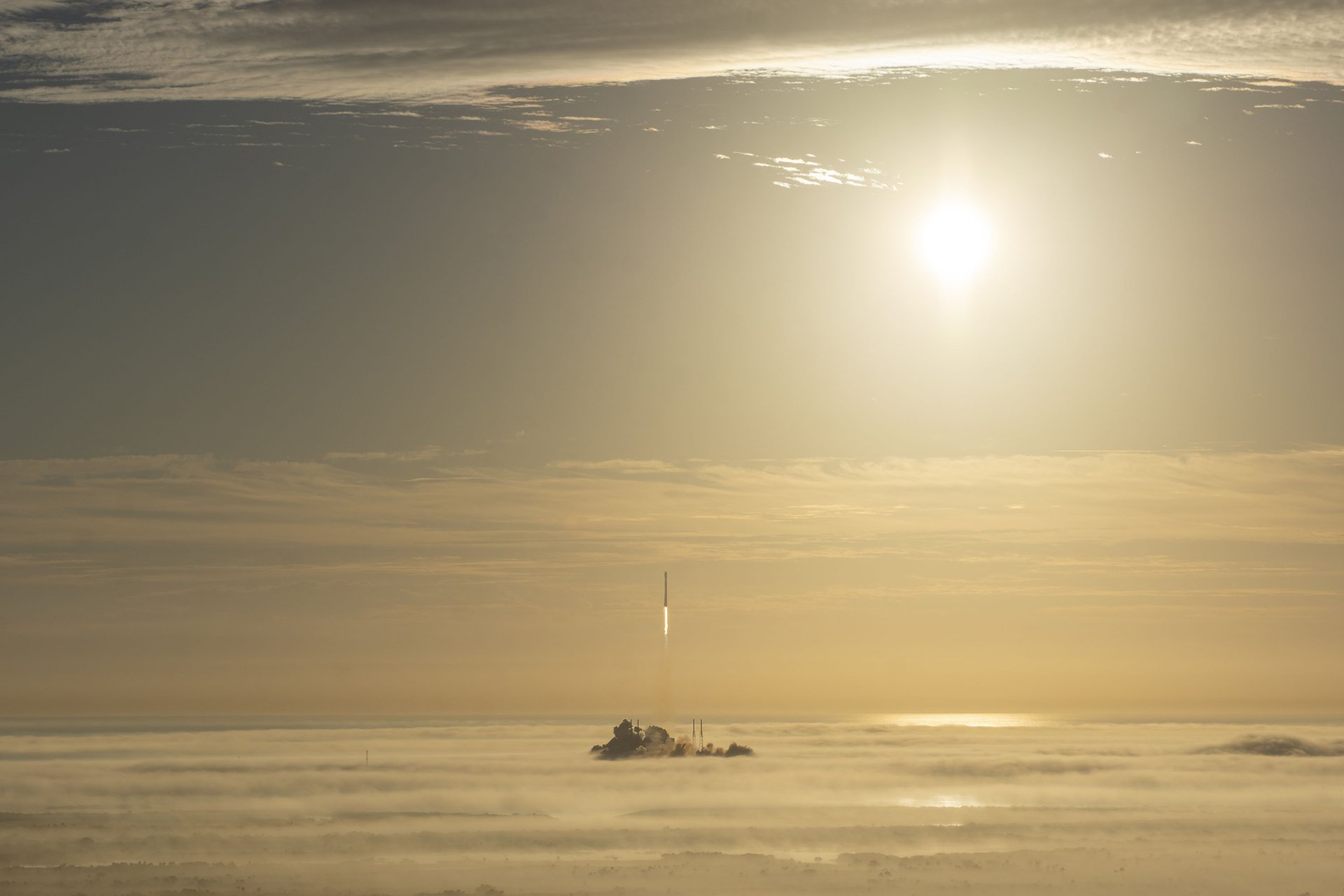 SpaceX rocket ascending through a foggy sky at sunrise, captured as a high-definition PC desktop wallpaper showcasing advanced technology and atmospheric beauty.