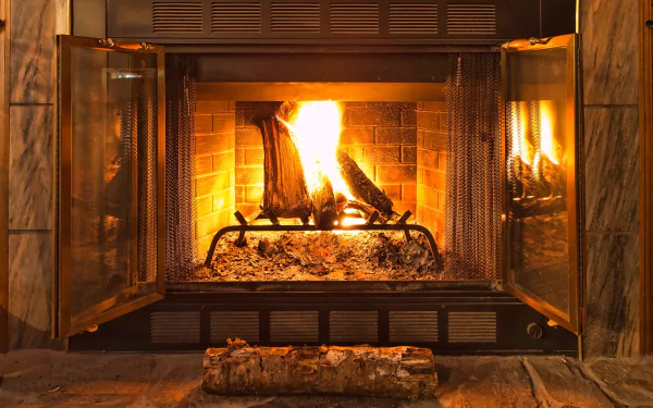 HD desktop wallpaper of a cozy lit fireplace enclosed in a stone mantel, creating a warm, inviting atmosphere.