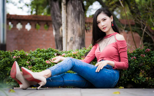 4K Ultra HD PC desktop wallpaper of a seated woman with long black hair in a pink top and jeans, reclining on a garden wall amid greenery.