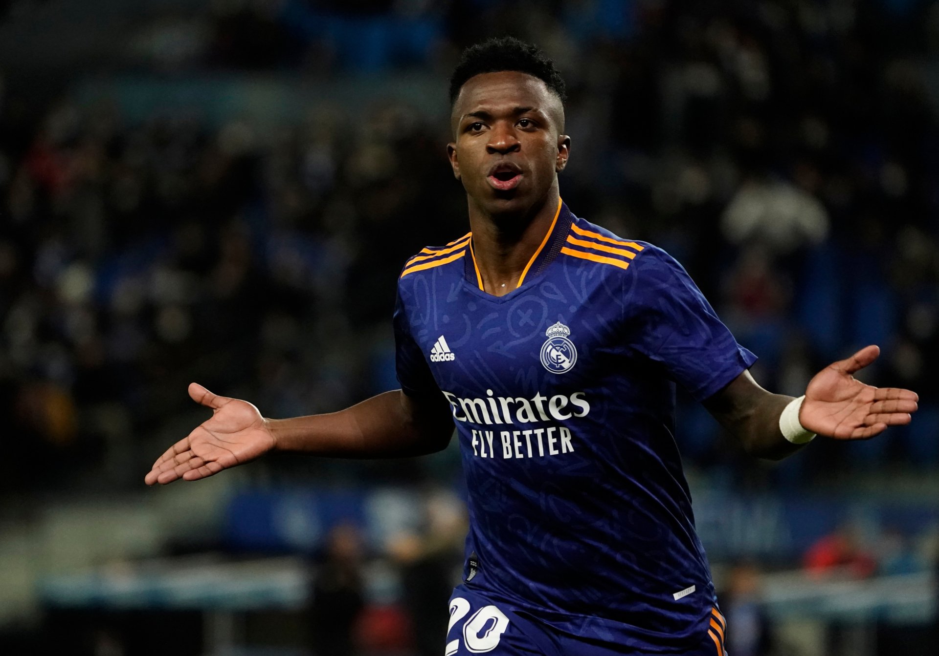 HD PC desktop wallpaper featuring Vinícius Júnior in action, wearing Real Madrid’s dark blue sports kit during a match.