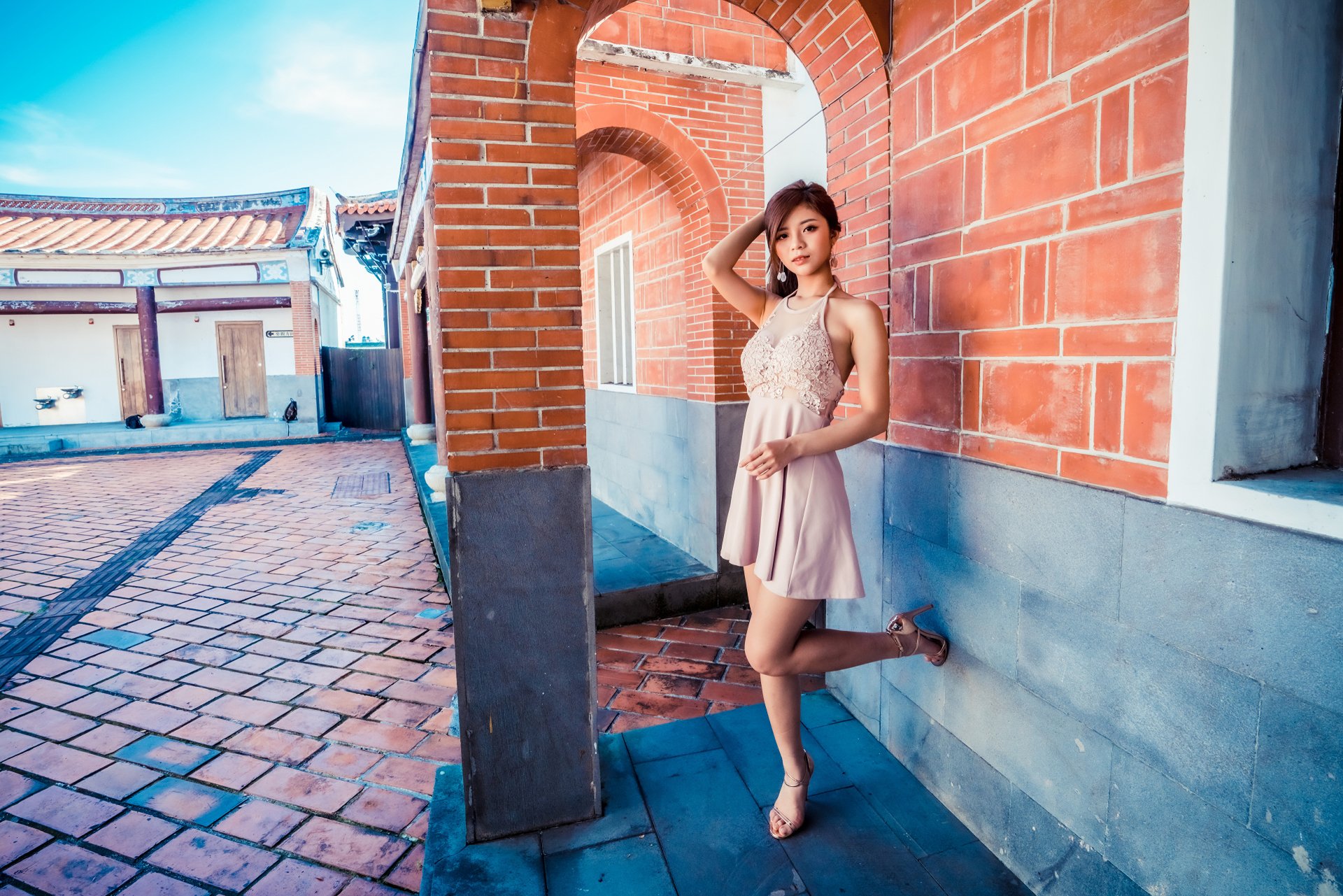 Asian woman in a dress poses against a red brick archway on a sunny day, captured in vibrant detail for a 4K Ultra HD PC desktop wallpaper and background.