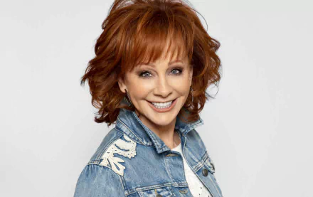 Smiling woman with red hair in a denim jacket posing for a vibrant HD desktop wallpaper background.