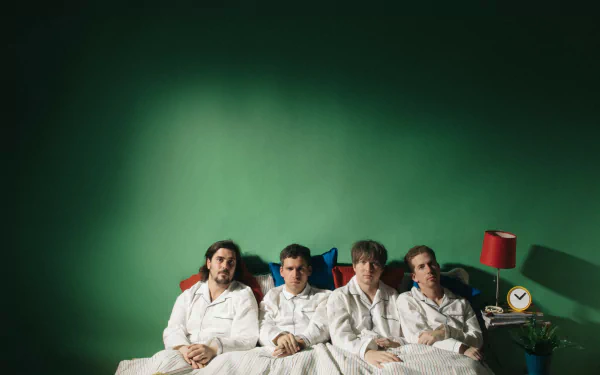 A captivating HD desktop wallpaper featuring Parquet Courts, showcasing the band members lounging in bed against a vibrant green background.
