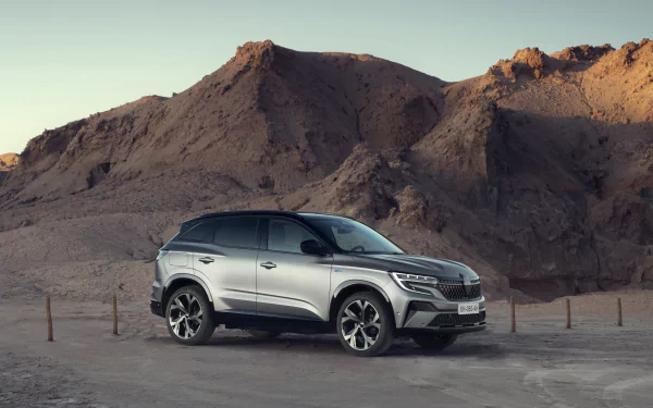 8K Ultra HD PC desktop wallpaper: silver Renault Austral E-TECH Hybrid SUV parked before rugged desert cliffs at dusk, vehicle shown in a dramatic side profile.