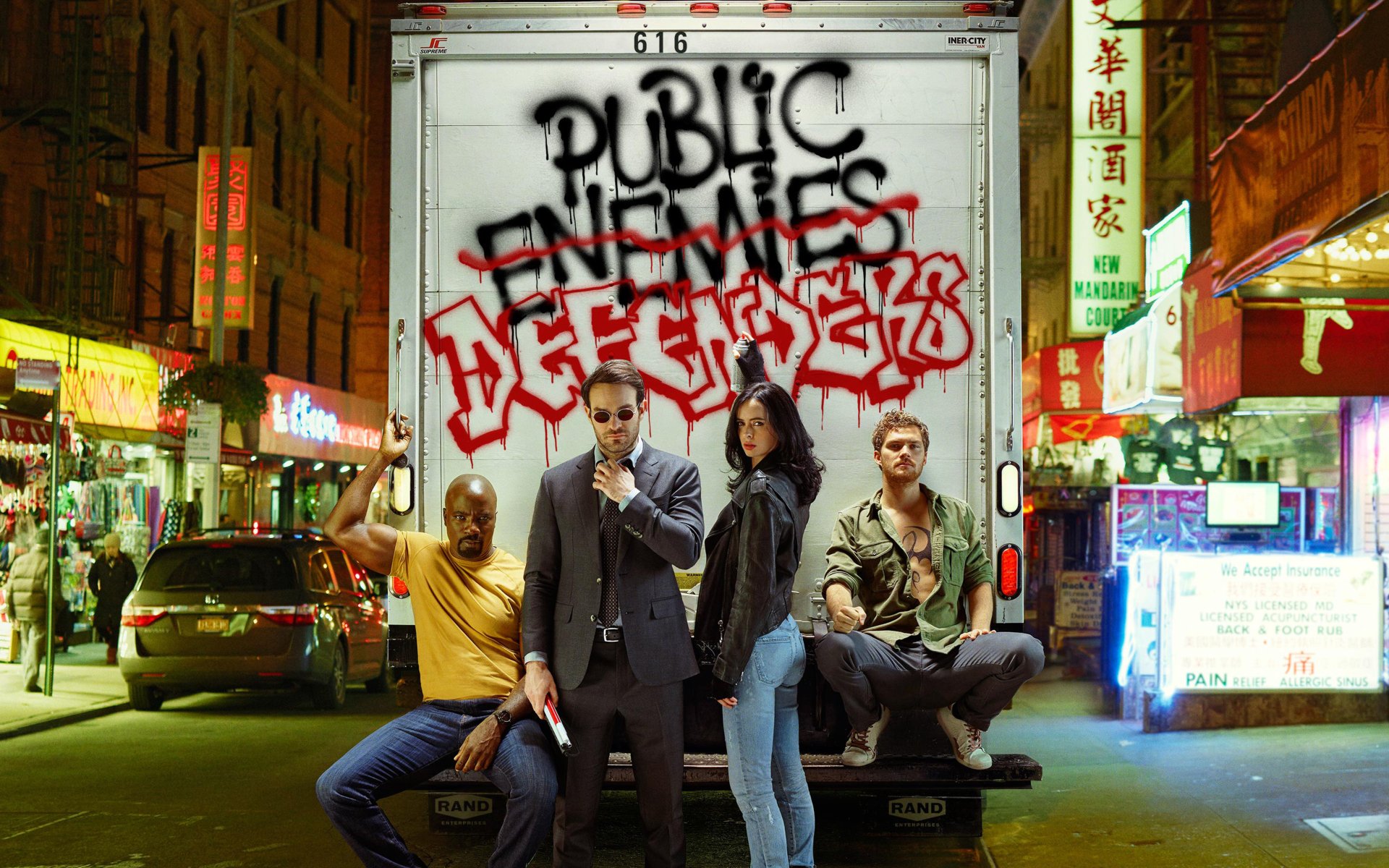 HD wallpaper featuring Marvel's The Defenders: Daredevil, Jessica Jones, Luke Cage, and Iron Fist, against an urban backdrop with Public Enemies spray-painted on a truck.