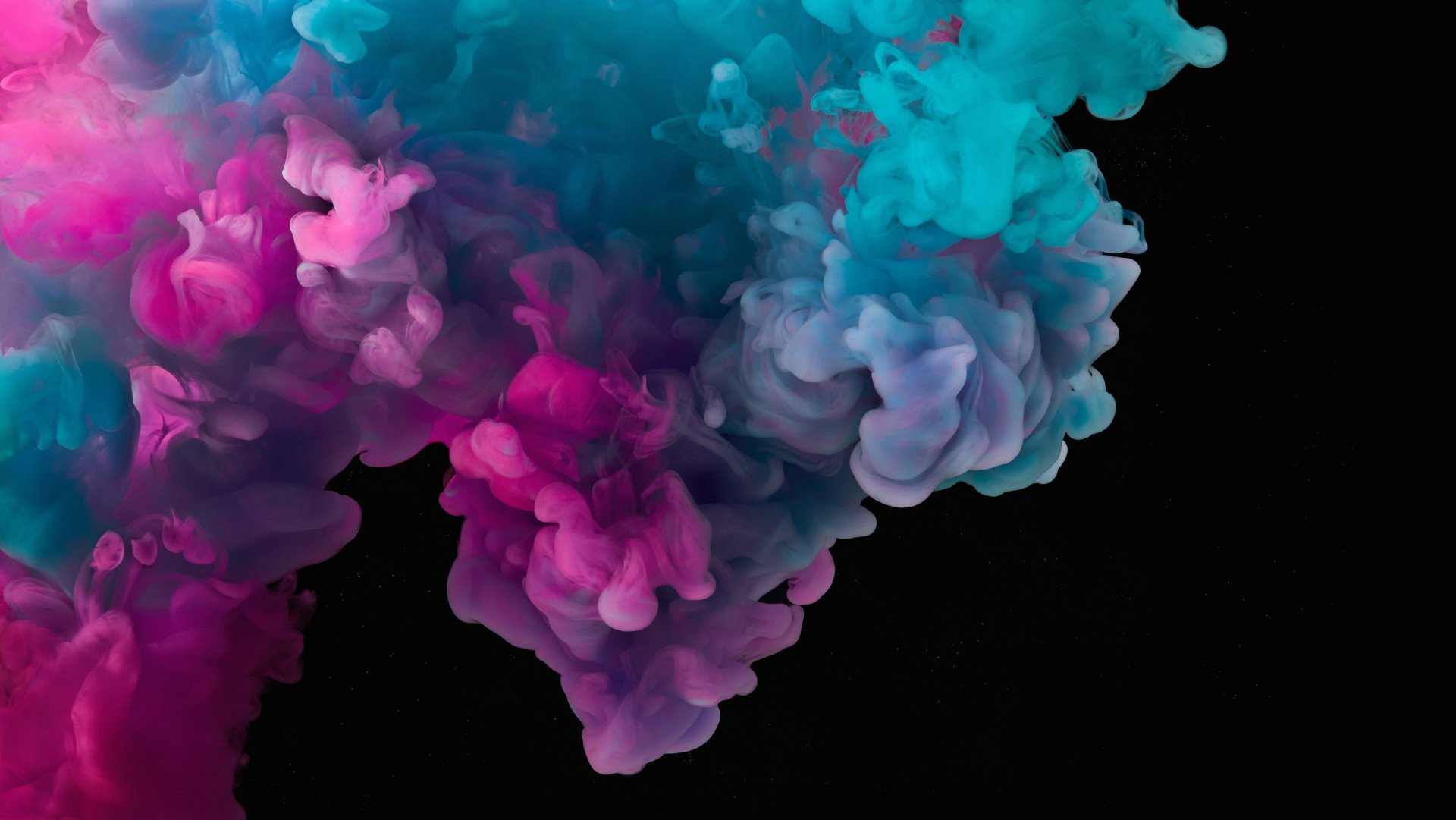 Abstract smoke in vibrant pink and blue hues swirls against a dark background, captured in stunning 4K Ultra HD as a striking PC desktop wallpaper.