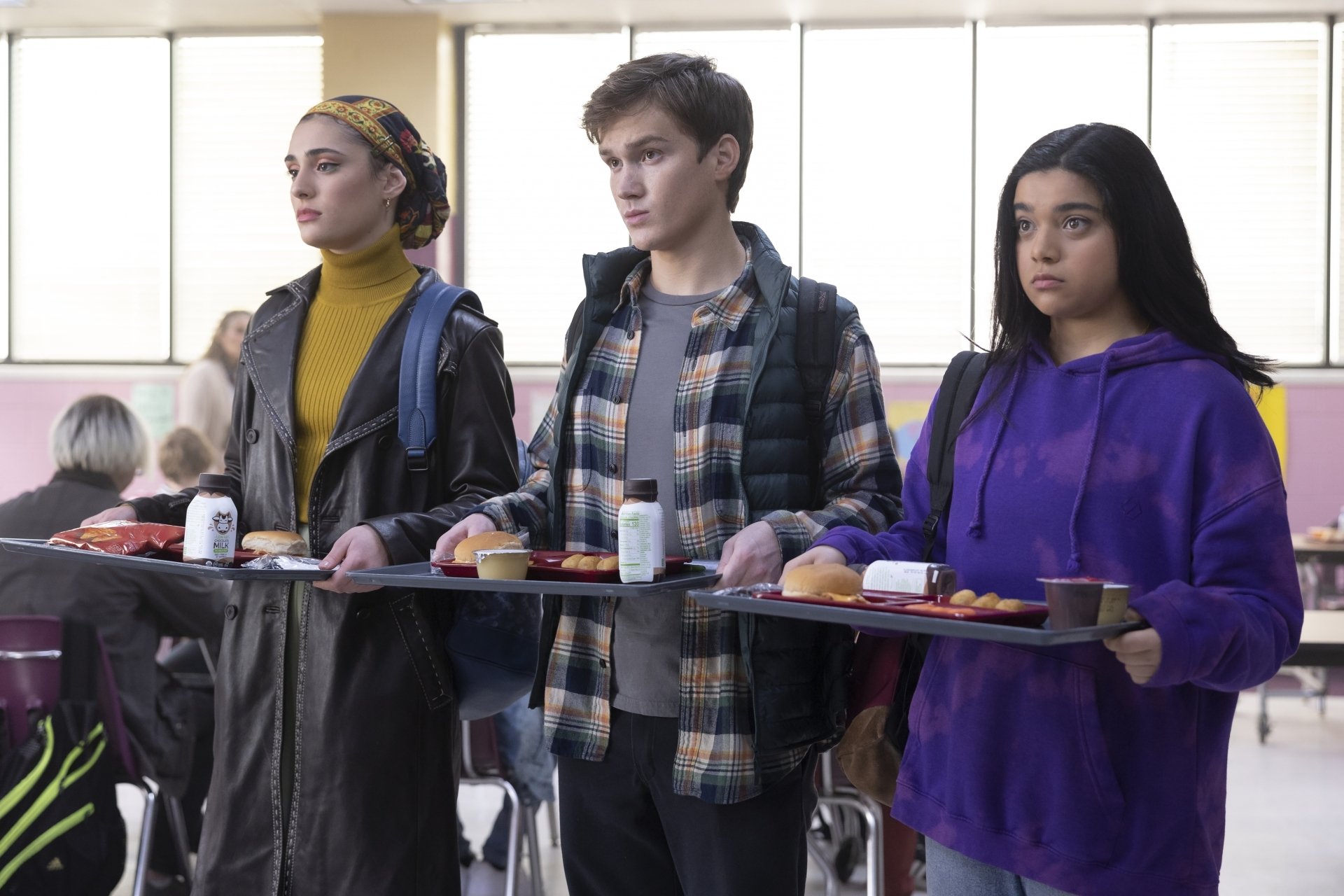 Three students in a school cafeteria from the TV show Ms. Marvel hold lunch trays — 4K UHD desktop wallpaper-style image.