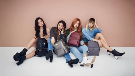 BlackPink members sitting against a peach wall, each holding a stylish backpack, featured in a 4K Ultra HD PC desktop wallpaper celebrating music and fashion.
