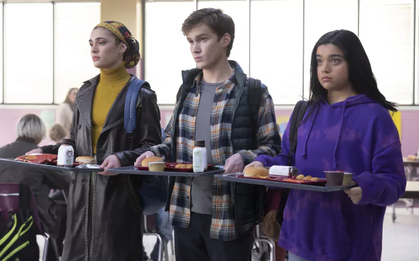 Three students in a school cafeteria from the TV show Ms. Marvel hold lunch trays — 4K UHD desktop wallpaper-style image.