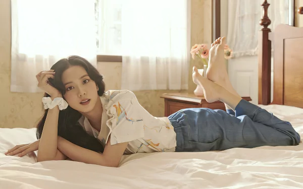 HD PC desktop wallpaper featuring a member of BlackPink lying on a bed in a softly lit room, blending music and serene aesthetics.