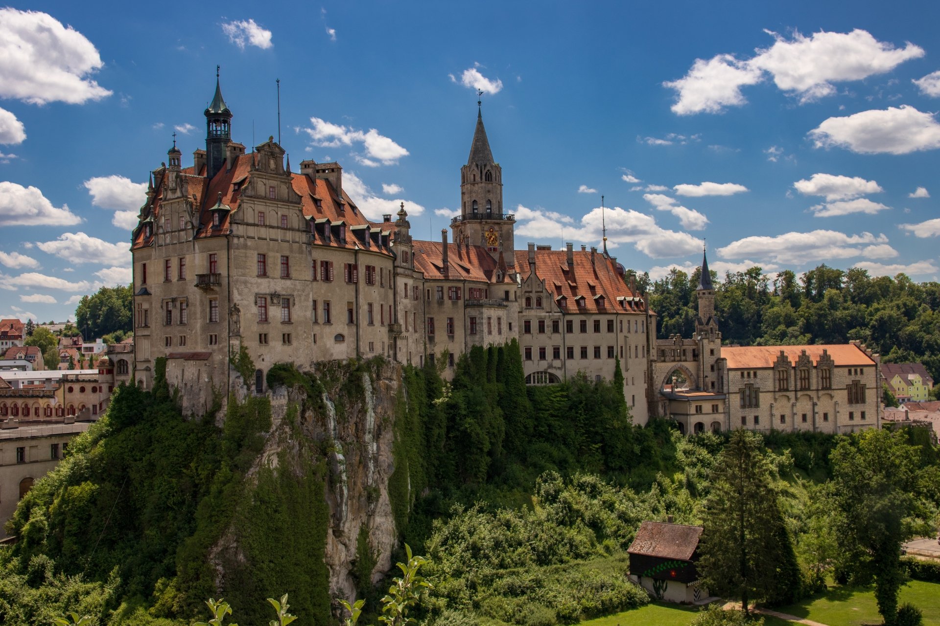 Sigmaringen Castle, Germany — a man-made fortress atop a limestone cliff above green forest, shown as a 5K Ultra HD PC desktop wallpaper beneath blue sky and scattered clouds.