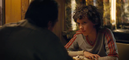 Millie Bobby Brown as Eleven from Stranger Things in a 4K Ultra HD scene, featuring a tense moment from the TV show with detailed indoor lighting and atmosphere.