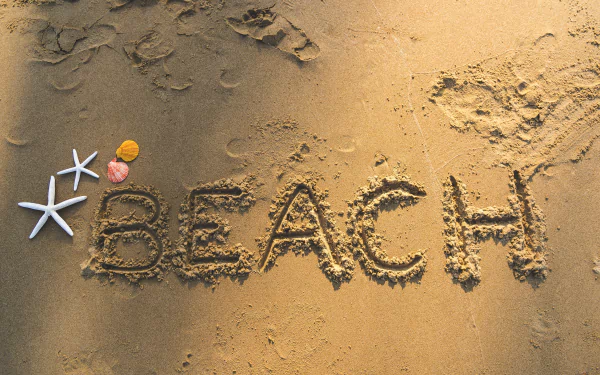 A stunning beach artwork displayed as an HD desktop wallpaper, featuring intricate sand art designs against a scenic coastal backdrop.