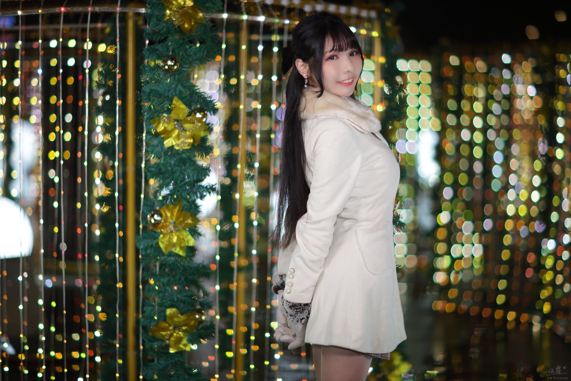 Smiling Asian woman in a white coat posing among festive bokeh lights — 4K Ultra HD PC desktop wallpaper and background.