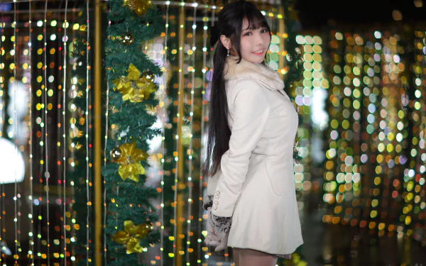Smiling Asian woman in a white coat posing among festive bokeh lights — 4K Ultra HD PC desktop wallpaper and background.