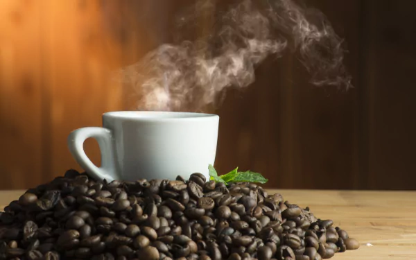 5K Ultra HD PC desktop wallpaper and background — steaming white coffee cup rising from roasted beans on a wooden table, warm brown backdrop (food, coffee).
