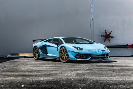 Sky-blue Lamborghini Aventador SVJ with bronze wheels parked by a gray wall, vivid 5K Ultra HD PC desktop wallpaper/background.