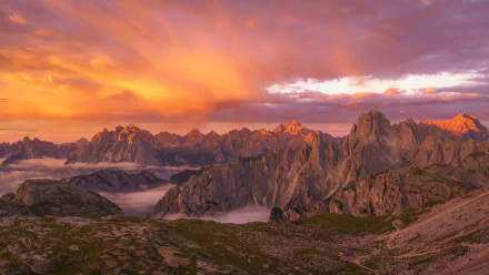2K Quad HD PC desktop wallpaper background of the Dolomites in the Alps: rugged alpine nature with golden sunrise lighting jagged peaks above mist-filled valleys.