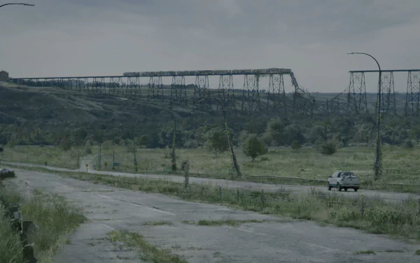 4K Ultra HD PC desktop wallpaper and background from the TV show The Last Of Us: overgrown highway, lone car, sagging power towers beneath a gray sky.