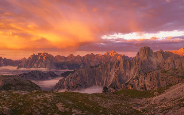 2K Quad HD PC desktop wallpaper background of the Dolomites in the Alps: rugged alpine nature with golden sunrise lighting jagged peaks above mist-filled valleys.