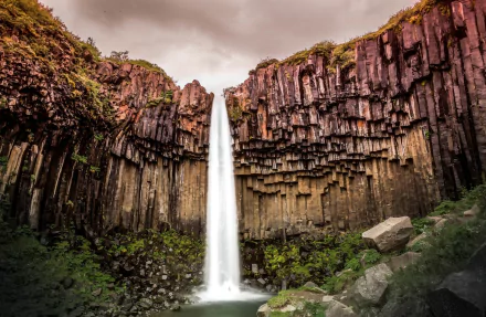 HD desktop wallpaper showcasing the Svartifoss waterfall framed by striking basalt columns in a lush natural landscape.